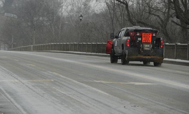A lone truck spreads salt on a traffic-free Chatham Bridge as a mix of snow, sleet and rain falls on Fredericksburg, Va., Sunday, Dec. 8, 2013. Snow, sleet and freezing rain pelted the Fredericksburg region on Sunday, making walking and driving conditions difficult. (AP Photo/The Free Lance-Star, Peter Cihelka)